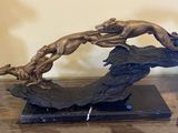 une sculpture en bronze représentant un chien sautant par-dessus un rocher
