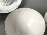 a white bowl sitting on a table next to a cup and saucer
