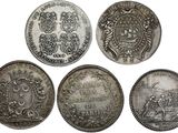 four silver coins of different sizes and shapes on a white background
