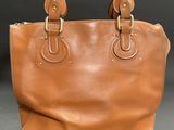 a brown leather handbag on a black background