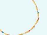 a gold necklace with turquoise and red beads on a white background