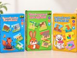 Trois puzzles pour enfants sont posés sur une table, devant une plante en pot.