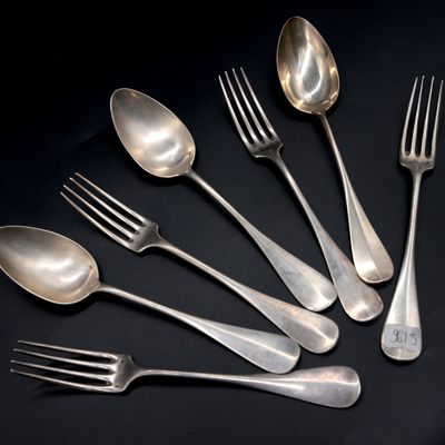 six silver spoons and a fork on a black surface