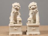 pair of white foo foo foo statues on a table against a gray background