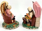 two figurines of people sitting in a chair