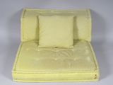 a yellow chair with pillows on top of it