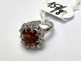 une photo d'une bague en argent sertie d'une pierre marron entourée de diamants blancs