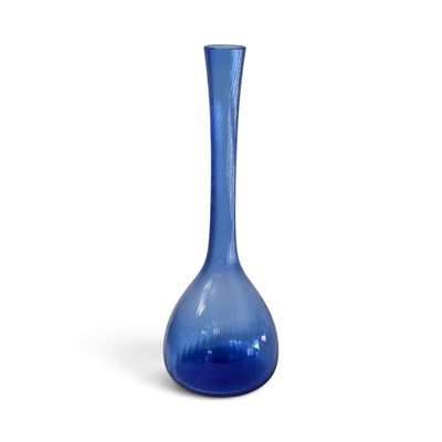 un vase en verre bleu posé sur une surface blanche
