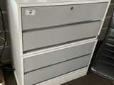 a white chest of drawers in a room with a black chair
