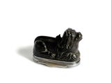 une photo d'une figurine de chien noire et argentée posée sur une surface blanche