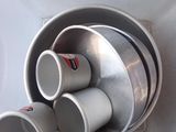 Plusieurs tasses sont empilées dans un saladier en métal posé sur une table