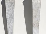 three stone statues of a man and a woman on a white surface