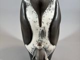 sculpture of a penguin sitting on its hind legs with a baby bird in its beak