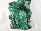 a green statue of a woman sitting on a rock