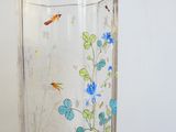 a glass vase with blue flowers and insects on it