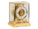 une horloge en or posée sur une surface blanche