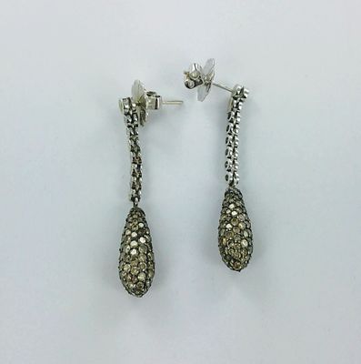 a pair of earrings with diamonds on them sitting on a white surface