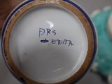 a person holding a blue and white vase with writing on it