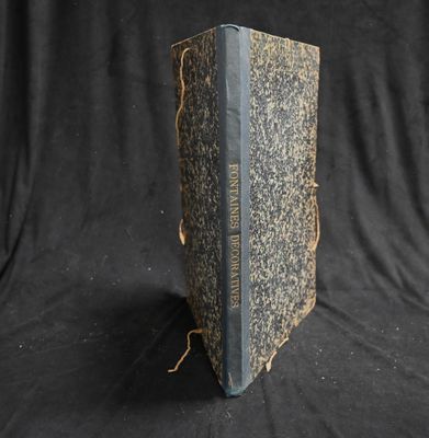 an old book sitting on top of a black cloth covered table