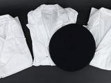 trois paires de pantalons blancs et un chapeau noir posés sur une surface noire