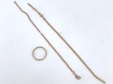 two rings and a gold chain on a white surface