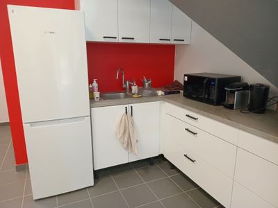 une cuisine avec un réfrigérateur blanc et un mur rouge