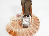 a watch sitting on top of a shell on a white surface