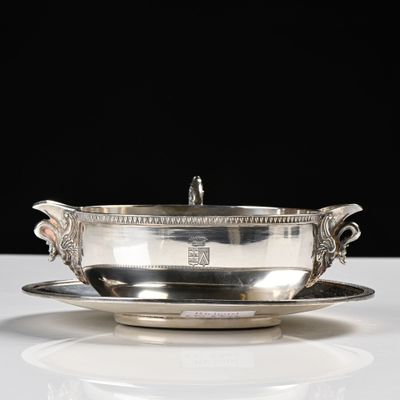 un service en argent ancien composé d'un bol et d'une soucoupe, posé sur une table blanche