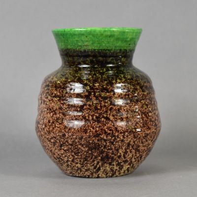 un vase vert et marron posé sur une table