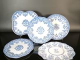 trois assiettes bleues et blanches et un bol posés sur une table noire