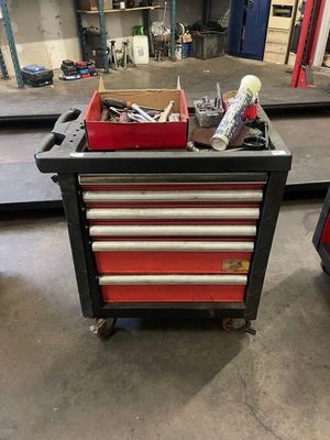 a red tool box with tools on it in a garage