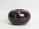 a black and red vase sitting on a white surface