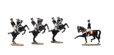 four figurines of men riding horses on a white surface