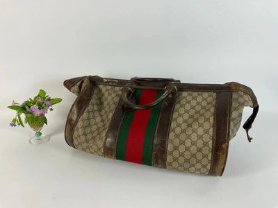 un sac marron et vert posé à côté d'un vase de fleurs