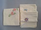 three folded napkins with embroidered flowers on them on a table