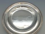 une assiette en argent posée sur une table blanche, sur fond noir