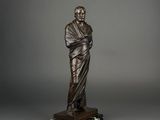 a bronze statue of a man holding a book on a marble base