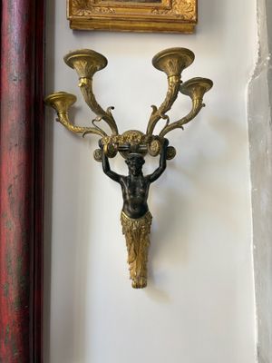 a picture of a clock on the wall next to a wall sconce