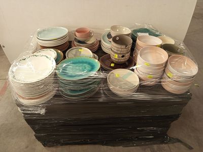 de nombreuses assiettes et bols posés sur une palette dans un entrepôt