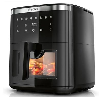 une friteuse à air chaud noire contenant des aliments, posée sur une surface blanche