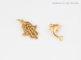 two gold charms of a dolphin and a hand on a white background