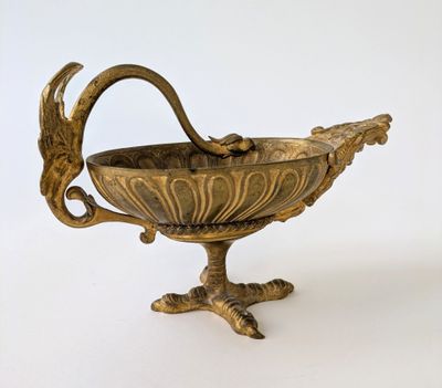 a metal bowl with a bird on it on a stand