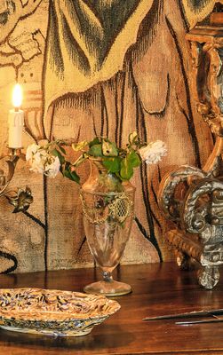 un tableau accroché au mur derrière une table sur laquelle se trouvent un vase et une bougie
