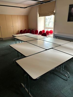 une pièce avec des tables et des chaises, et un tableau accroché au mur