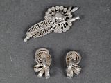 two silver brooches and a pair of shoes on a table