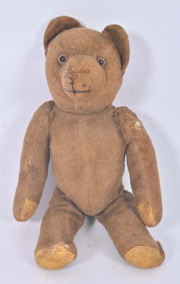 un ours en peluche marron assis sur une surface blanche