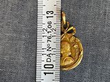 an image of a gold coin being held by a ruler