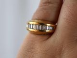 la main d'une femme tenant une bague en or sertie d'une rangée de diamants