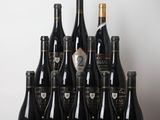 Des bouteilles de vin sont alignées sur une table devant un mur blanc.