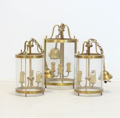 trois bougeoirs en verre et en laiton posés sur une surface blanche